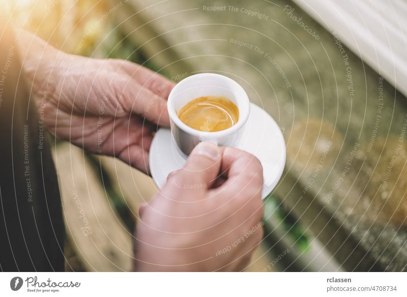Ein Mann hält eine frische Tasse heißen Espresso in einem Café Barista Kaffee Werkzeuge Halt Kunst Barmann Getränk Crema Dolce Vita Werkstatt altehrwürdig Sucht