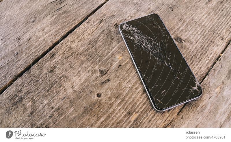 Modernes Mobiltelefon mit kaputtem Bildschirm auf hölzernem Hintergrund Telefon Riss Smartphone gebrochen Zelle zerkratzen zerschlagen Funktelefon Zifferblatt