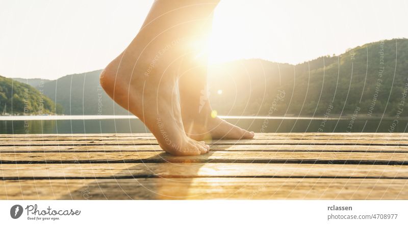 Beine auf Steg von einer jungen Frau bei Sonnenuntergang. Yoga-Konzeptbild Barfuß Anlegestelle See Fuß Liebe Lifestyle eintauchend sich[Akk] entspannen
