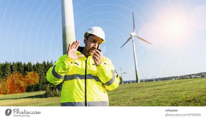 Ingenieur, der an einer Windkraftanlage arbeitet und mit dem Walkie-Talkie spricht, um die Arbeit zu kontrollieren Walky Mann Turbine Schutzhelm Windmühle