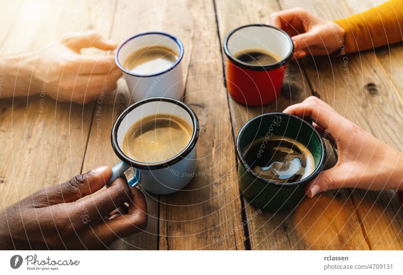 Gruppe von Freunden trinkt Cappuccino in einem Bar-Restaurant - Menschen Hände jubeln und stoßen an - Konzept des geselligen Beisammenseins mit weißen und schwarzen Männern und Frauen zusammen
