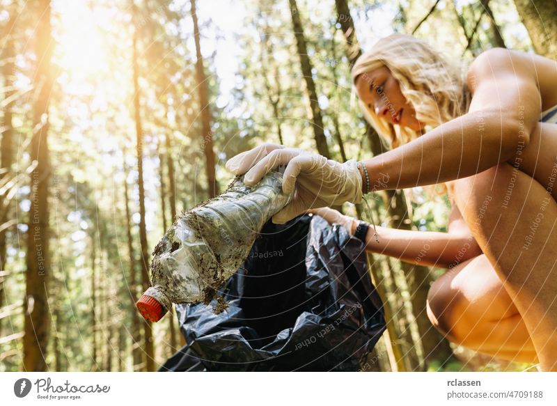 Frau Abholung eines Mülls Plastikflasche für die Reinigung des Waldes, Natur und Umwelt Reinigung Konzeptbild. Abfall Werfen Sauberkeit Menschen Recycling