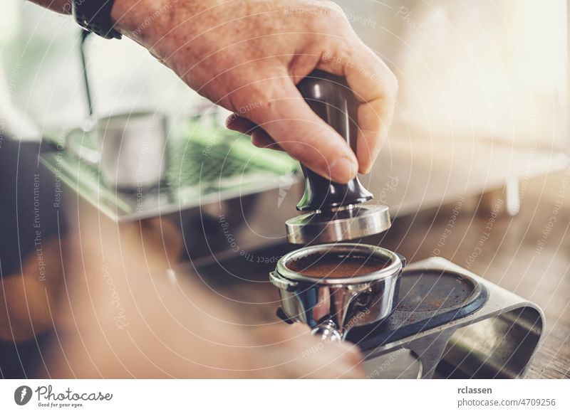 Kaffeemehl, das von einem Barista für frischen Espresso in den Filterhalter gepresst wird Hintergrund Getränk schwarz Business Café Pulver Portafilter Tasse
