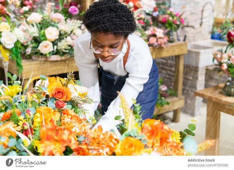 Schwarze Frau mit Blumen im Blumenladen Arbeiter Blumenstrauß Blumenhändler Pflanze Floristik Industrie Blütezeit Mitarbeiter professionell Flora Laden Job