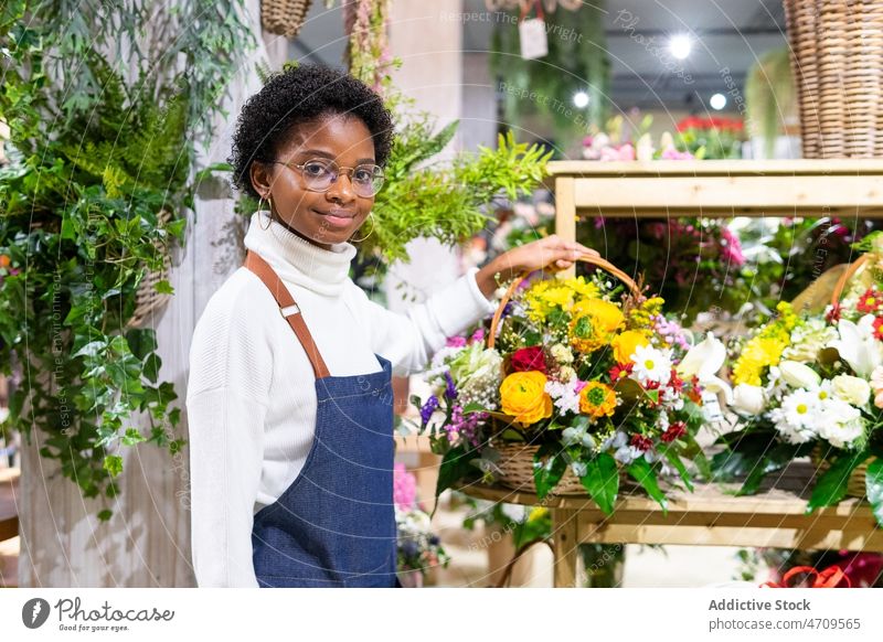 Lächelnde schwarze Frau mit Blumenstrauß im Korb Blumenladen Blumenhändler Arbeit Pflanze Floristik Industrie dekorativ Flora professionell Laden Job