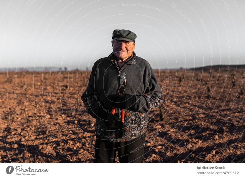 Positiver alter Mann mit Astschere auf dem Lande reif Stutzen Instrument Landwirt Feld Landschaft Ackerbau Agronomie ländlich Umwelt Gelände Licht Rentnerin