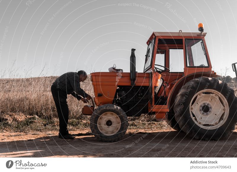 Alter Traktorfahrer nimmt Instrument aus Werkzeugkasten für Reparatur Mann Senior Fahrer Arbeit Feld männlich Landwirt Bauernhof Kasten Ackerbau Flugzeugwartung