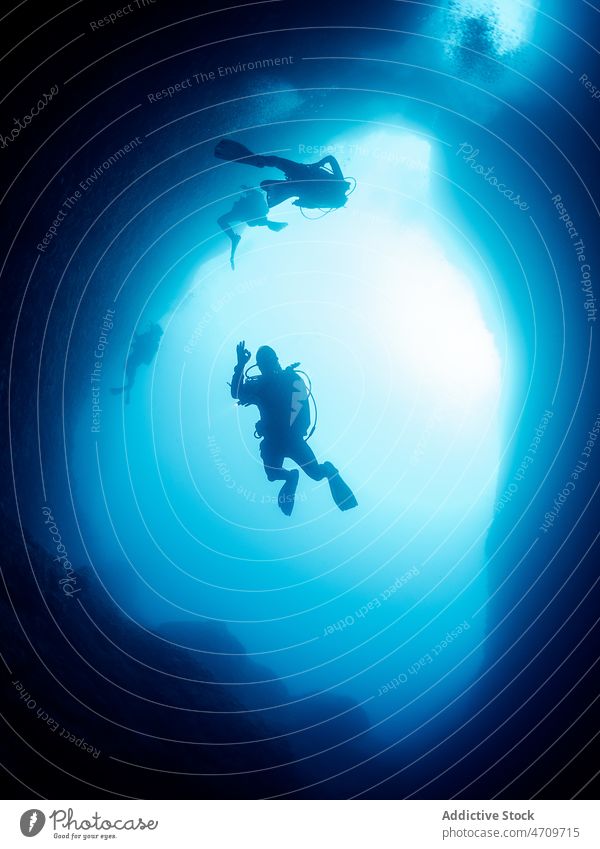 Taucher schwimmen zwischen Felsformationen MEER unter Wasser Sinkflug Höhle Felsen dunkel erkunden entdecken tief unterseeisch aktiv Meerwasser aqua Aktivität