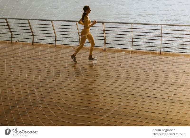 Junge Frau läuft auf der Uferpromenade Aktion aktiv Aktivität Erwachsener Athlet schön Körper hell Tag Übung trainiert. passen Fitness Gesundheit