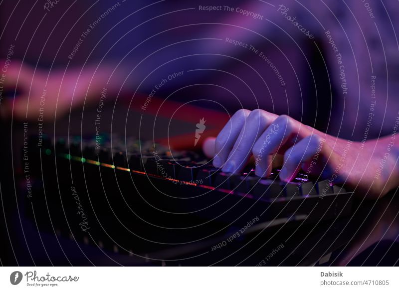 Gamer spielen ein Computerspiel, verwenden eine neonfarbene Tastatur Spiel Keyboard online Spieler cyber dunkel Sucht hintergrundbeleuchtet Spielen Licht RGB