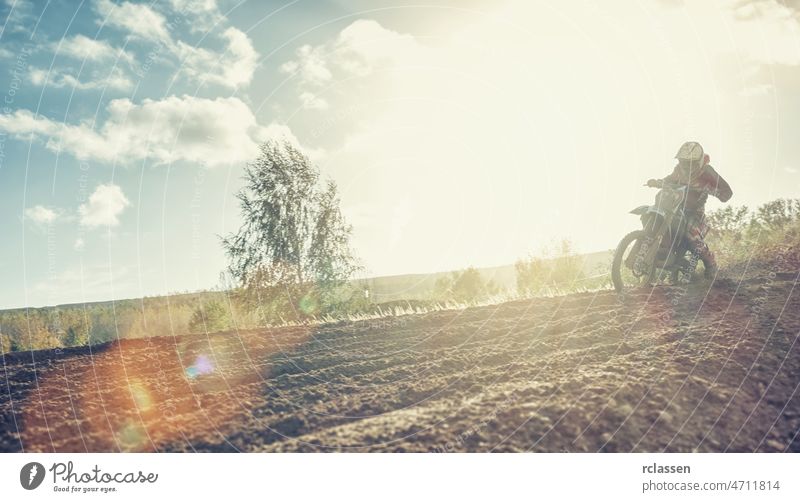 Enduro-Fahrer auf unbefestigter Strecke mit seinem Motocross-MX-Fahrrad bei Sonnenuntergang extrem enduro Rallye Dirtbike Staubwischen Schmutz Bahn Reiter