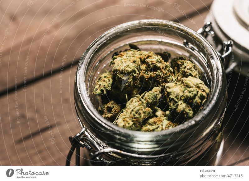 Medizinisches Marihuana oder Cannabisknospen in einem Gefäß Blütenknospen Unkraut Pflanze Ackerbau Hintergrund Erdöl cbd Panzer Holztisch Glas Medikament