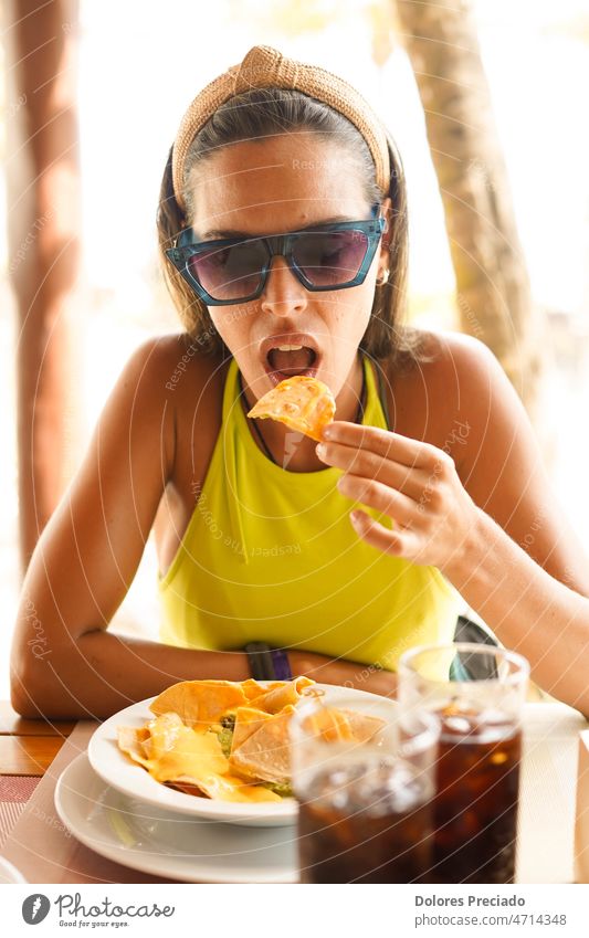 Eine junge Frau isst eine Portion Nachos mit Fleisch Erwachsener Alkohol Amuse-Gueule Avocado Strand schön Kaukasier Peperoni Chips Cocktail Mais lecker trinken