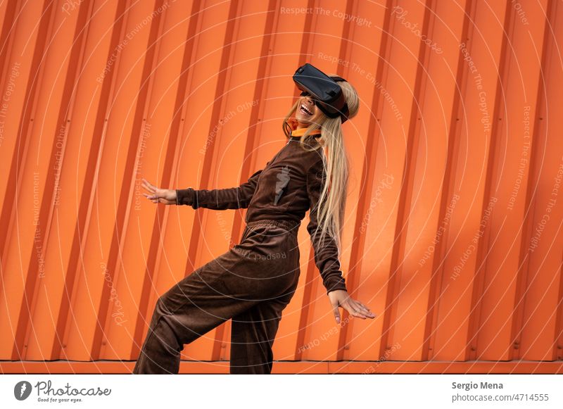 Fröhliche afroamerikanische Frau mit blondem Haar, die eine Virtual-Reality-Brille auf einem orangefarbenen Hintergrund trägt eine Person Afro-Look Amerikaner