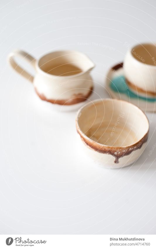Handgefertigtes Tongeschirr, Teller und Schalen auf weißem Tisch aus Ton. Töpferwaren Keramik traditionell Küchengeräte Fähigkeit Kreativität Tasse Beruf Objekt