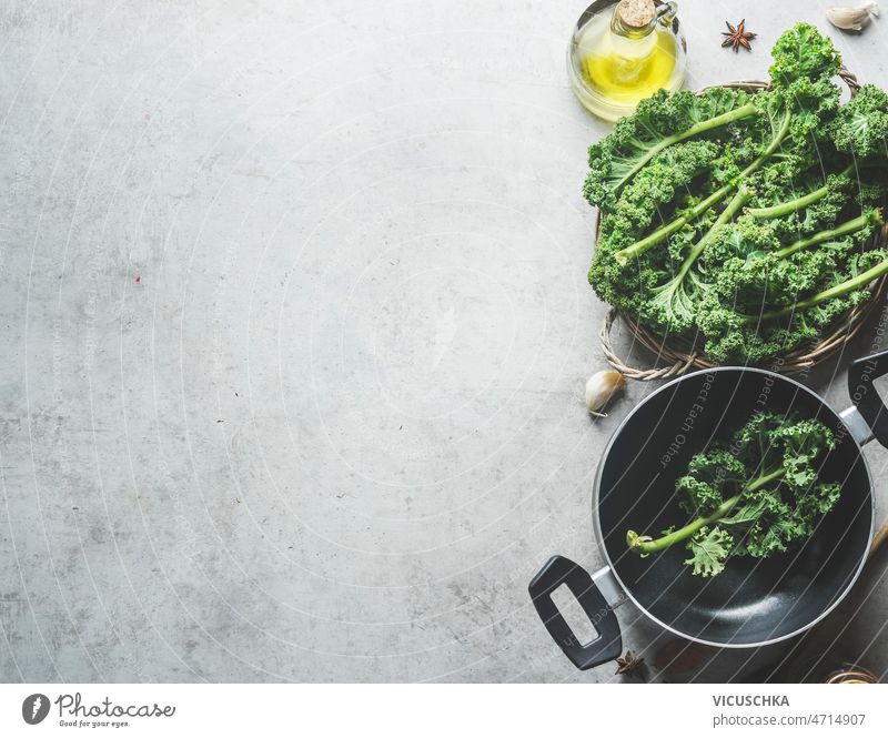 Lebensmittel Hintergrund mit grünen Grünkohl Blätter, schwarz Kochen Pfanne, Olivenöl Lebensmittelhintergrund Kale Kochpfanne Anis Knoblauch grau Beton