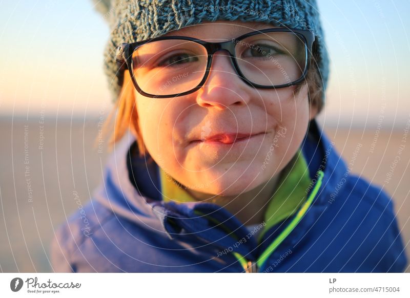 Kind mit Brille schaut neugierig in die Kamera und lächelt Gefühle geheimnisvoll Identität einzigartig lächelndes Gesicht lachendes Kind Lachen glückliche