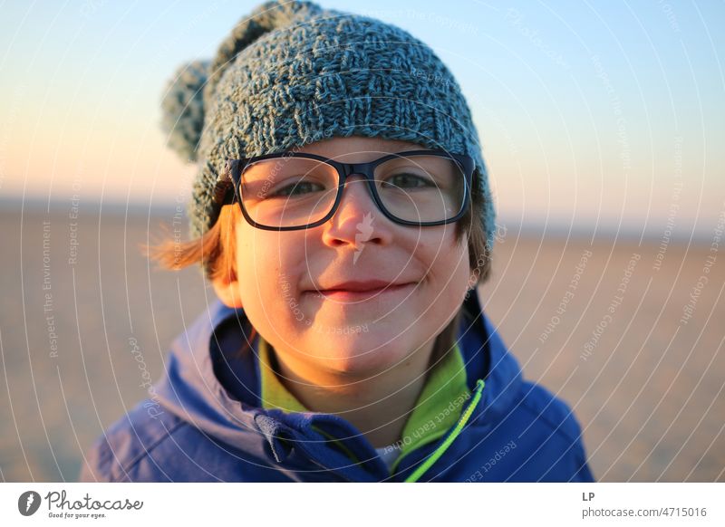 Kind mit Brille schaut neugierig in die Kamera und lächelt Gefühle geheimnisvoll Identität einzigartig lächelndes Gesicht lachendes Kind Lachen glückliche