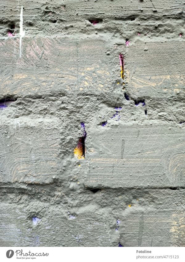 Die grau gestrichene Mauer war früher sicher einmal bunt. Das kann man nur noch an den Fugen sehen. Dort schimmert gelb und lila durch. Backstein Mauerstein