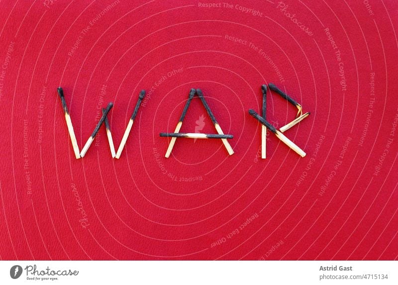Angebrannte Streichhölzer, die das Wort WAR bilden, auf einem roten Papieruntergrund krieg streichhölzer holz brennen brand abgebrand zerstört zerstörung