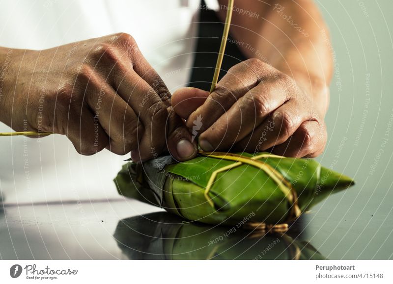 Peruanische Hände binden eine traditionelle Tamale mit Bananenblättern. tamal Kopplungsbindung lecker Hand Lebensmittel Blatt Küche Honduras Panama Mexiko
