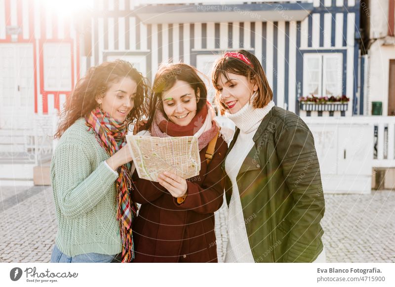 Touristinnen lesen eine Karte vor bunten Häusern an der Costa Nova, Aveiro, Portugal Freunde Frauen reisen Landkarte Backpacker Tourismus Kaukasier Freundschaft