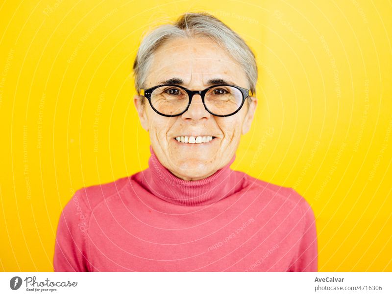 Alte Frau Nahaufnahme lächelnd in die Kamera glücklich posiert isoliert über gelbe Farbe Wand Hintergrund. Tägliche Ausdrücke mit Kopie Raum im Studio. alt