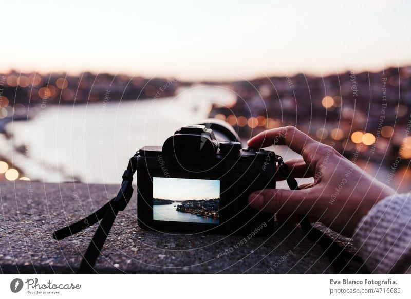 Nahaufnahme einer Frau auf der Brücke von Porto, die bei Sonnenuntergang Fotos mit der Kamera macht. Tourismus in der Stadt Europa abschließen unkenntlich