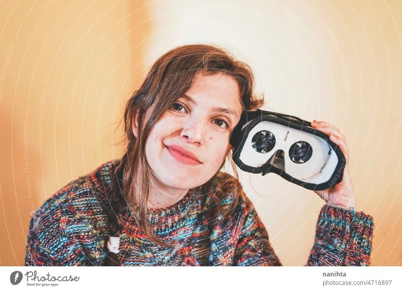 Lustiges Porträt einer jungen Frau, die eine VR-Brille aus Pappe hält Metaversum im Inneren Linse Technik & Technologie nachhaltig Karton spielerisch Spieler