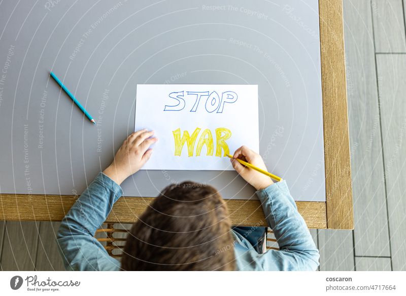 Kleines Kind zeichnet Stop War auf ein Papier. Ukraine Russland Krieg Konzept. weg von der ukraine blau gelb Junge Kinder gegen den Krieg Färbung Farben