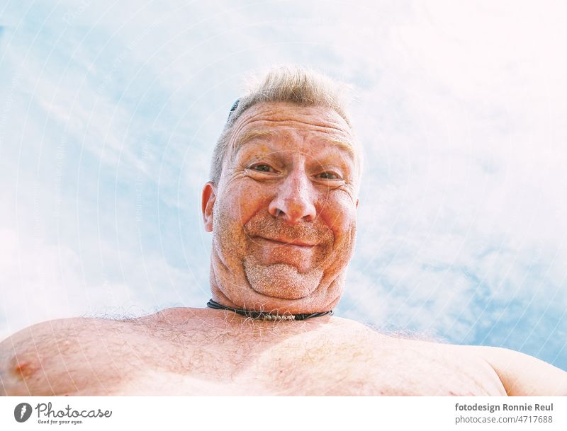 Unrasierter, behaarter Mann mit freiem Oberkörper und Doppelkinn aus Untersicht am Strand Farbfoto 50 bis 60 Jahr Gesicht Kamerablick Porträt Männerbrust Kinn