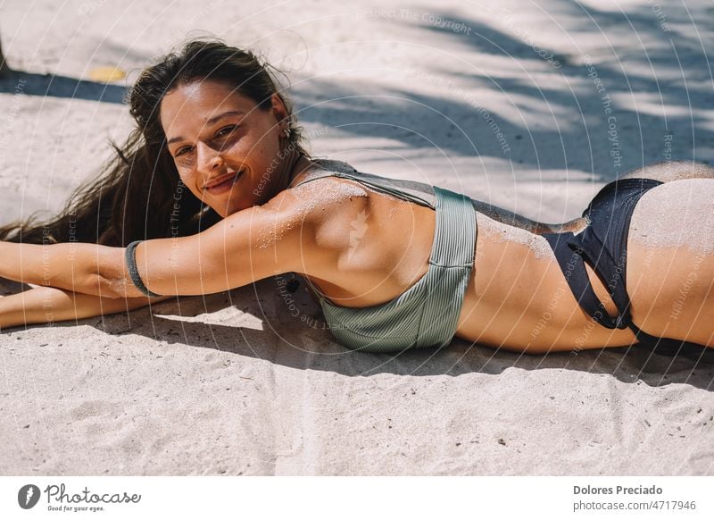 Weibliches Modell posiert im Bikini auf dem Sand eines paradiesischen Strandes liegend attraktiv Hintergrund Transparente schön Schönheit Körper brünett