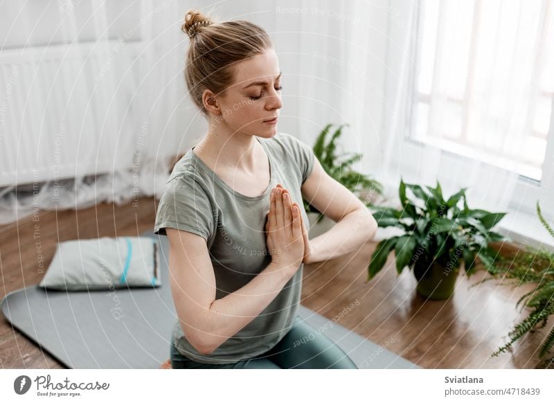 Schöne junge Frau macht Übungen und macht Yoga zu Hause heimwärts praktizieren Körper Lifestyle Fitness Training Meditation Unterlage Sport sportlich