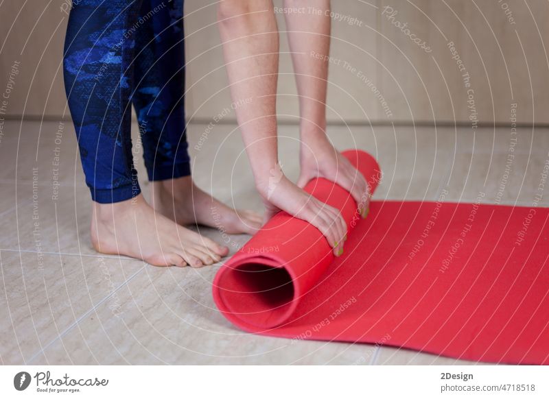 Frau faltet blaue Übungsmatte auf Holzboden vor oder nach dem Training im Yogastudio, Club oder zu Hause Person Sport Lifestyle Fitnessstudio Unterlage Hand