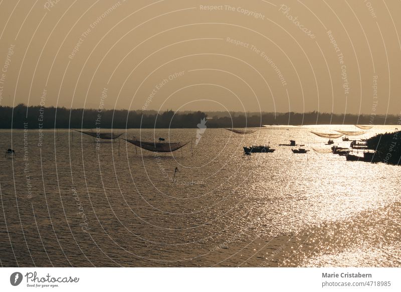 Luftaufnahme, Silhouetten von traditionellen Netzen und Fischerbooten bei Sonnenuntergang im Fischerdorf Thanh Nam in Hoi an Vietnam Drohnen-Schuss Aufzugsnetze