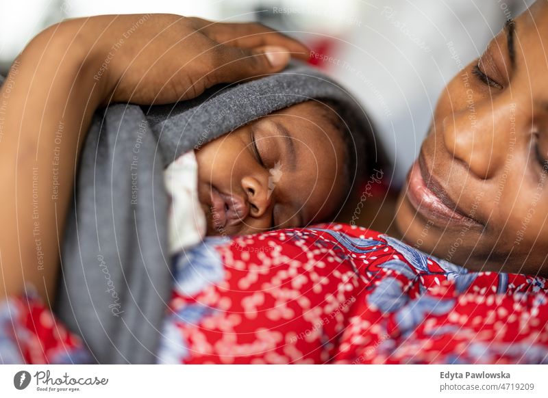 Mutter kuschelt schlafendes Baby zu Hause Mama Kinder neugeboren Familie Mutterschaft echte Menschen im Innenbereich heimwärts flach Appartement genießen