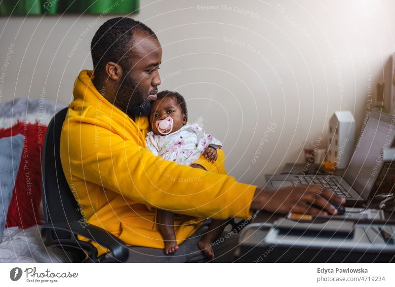 Mann hält sein neugeborenes Mädchen und arbeitet zu Hause am Laptop Vater Papa Kinder Familie Vaterschaft echte Menschen im Innenbereich heimwärts flach