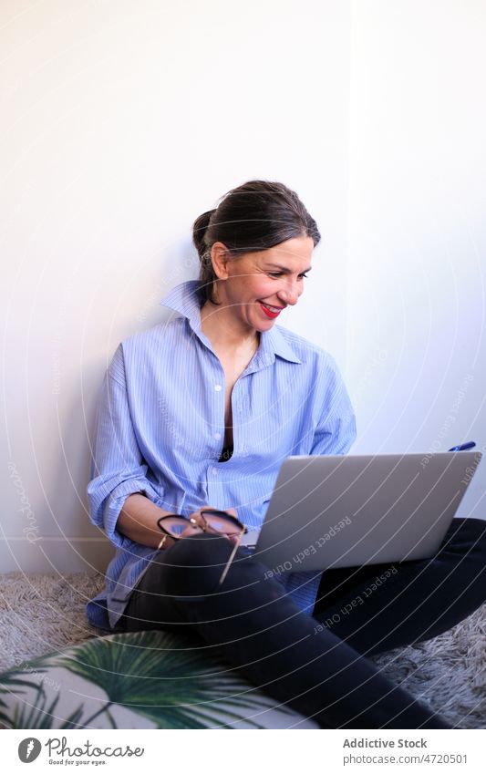 Fröhliche Frau mit Laptop, die auf ihrem Smartphone surft freiberuflich Textnachricht online Browsen Raum Internet digital Arbeit abgelegen Funktelefon positiv