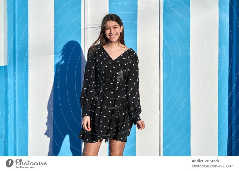 Lächelnde Frau in der Nähe einer mehrfarbigen Wand Straße Vorschein Stil feminin Mode Outfit Freizeit Kleidungsstück Bekleidung heiter Sommer jung positiv