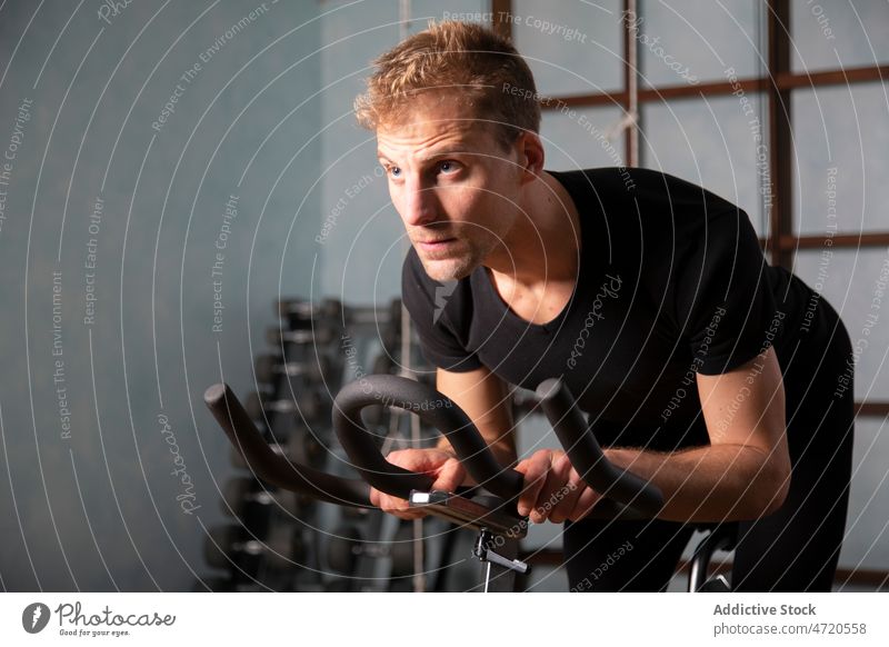 Selbstbewusster Mann, der in einem Fitnessstudio auf einem Radfahrgerät trainiert Sportler Zyklus Maschine Übung Training Bestimmen Sie selbstbewusst passen