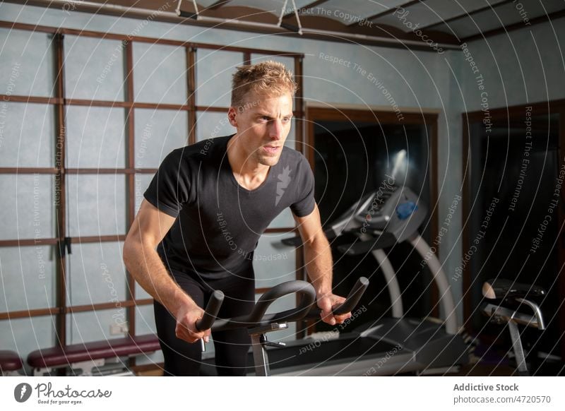 Selbstbewusster Mann, der in einem Fitnessstudio auf einem Radfahrgerät trainiert Sportler Zyklus Maschine Übung Training Bestimmen Sie selbstbewusst passen