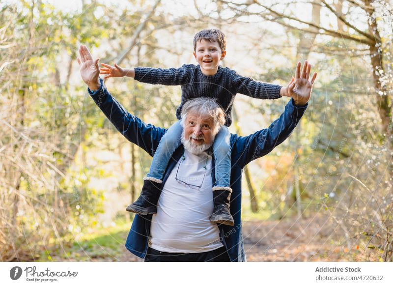 Fröhlicher älterer Mann mit Enkel auf den Schultern im Wald Lächeln Kind Park Halt Herbst Junge positiv Zusammensein männlich Glück heiter Großvater Senior