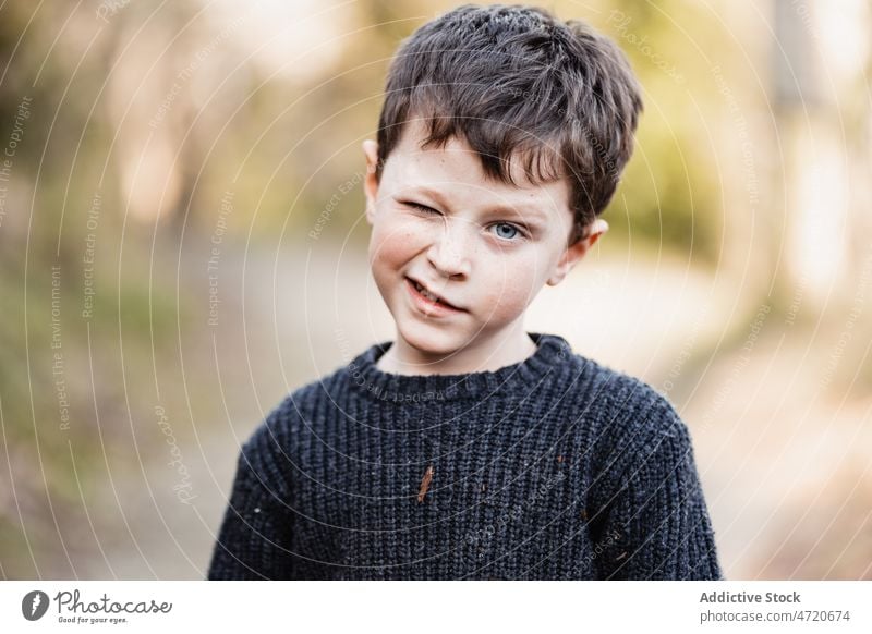 Junge im warmen Pullover zwinkert der Kamera zu Kind Zwinkern Porträt Persönlichkeit Kokette Individualität charmant Blick spielerisch lustig Kindheit wenig