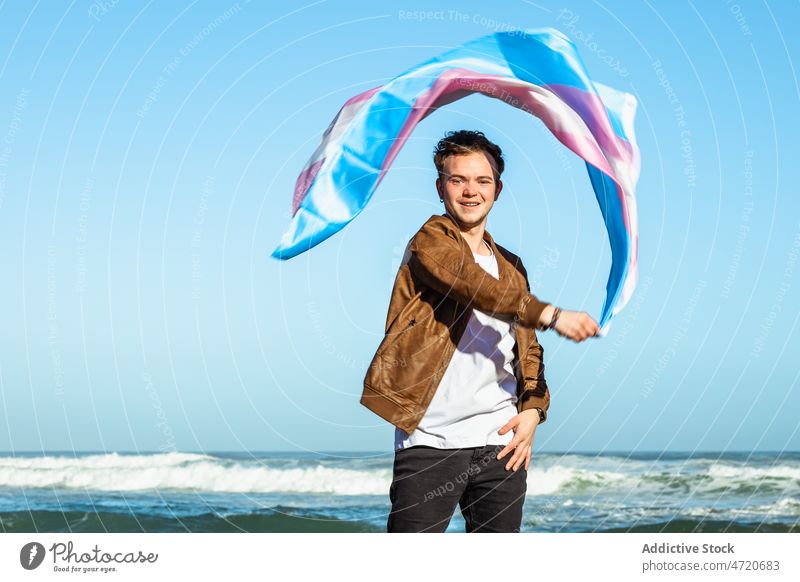 Zufriedener Mann mit bunter Transgender-Flagge am Meer Fahne lgbtq Identität Freiheit gleich MEER Küste Natur Meeresufer Ufer männlich Strand Wasser winken