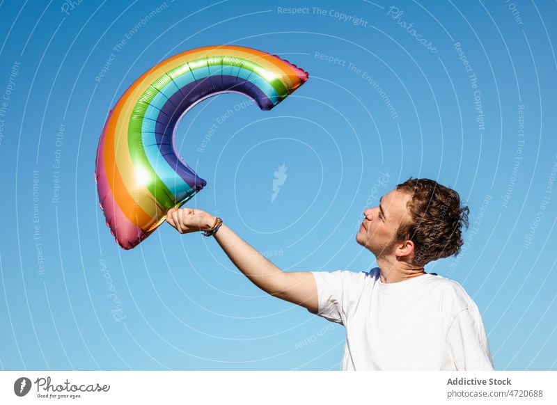 Fröhlicher Mann mit LGBT-Luftballon Transgender lgbt lgbtq Regenbogen Identität Freiheit gleich schwul Homosexualität Stolz Toleranz Symbol heiter Geschlecht