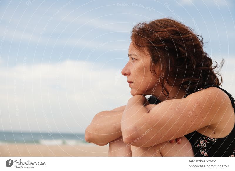Seitenansicht einer verträumten Frau, die am Strand sitzt Ufer MEER Meeresufer Erholung Zeitvertreib Freizeit ruhen Tourist Resort Sand Seeküste Meeresküste