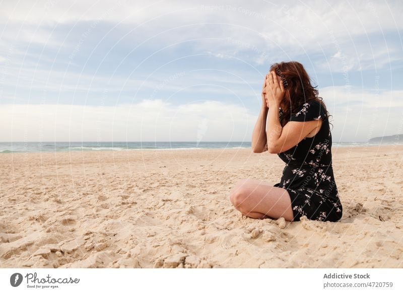 Frau sitzt am Strand und bedeckt ihre Augen mit ihren Händen Ufer MEER Meeresufer Erholung Zeitvertreib Freizeit ruhen Tourist Resort Sand Seeküste Meeresküste