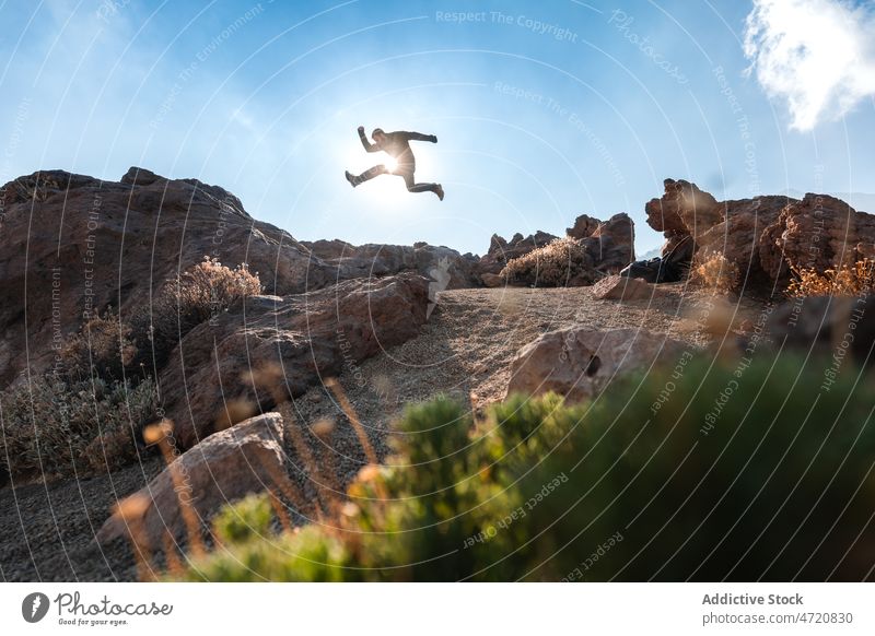 Mann springt über Felsen bei Sonnenlicht im Hochland Tourist springen Stein erkunden Fundstück Freiheit reisen Fernweh männlich Natur Reisender wild Umwelt