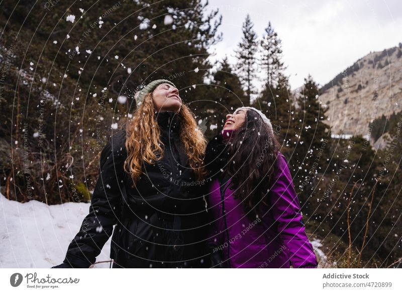 Fröhliche Frauen unter fallendem Schnee Freund Reisender Winter Wanderer Schneefall Zeitvertreib Hochland Spaß haben Wanderung Freizeit Freundschaft Bonden
