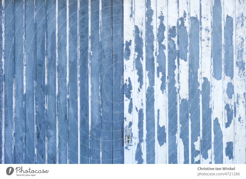 Ein altes verwittertes Garagentor. Die blaue und weiße Farbe blättert kunstvoll ab. Holz blau und weiss abblättern ungepflegt symmetrisch Hintergrundbild